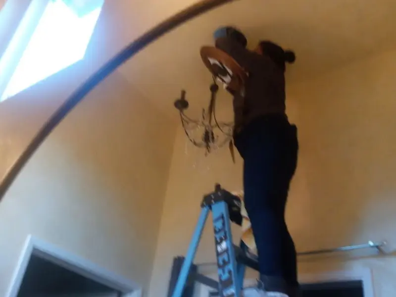 Electrician installing a chandelier in a Gladstone residence